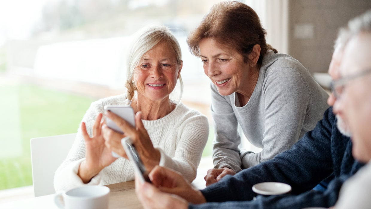two senior women looking at phone and smiling