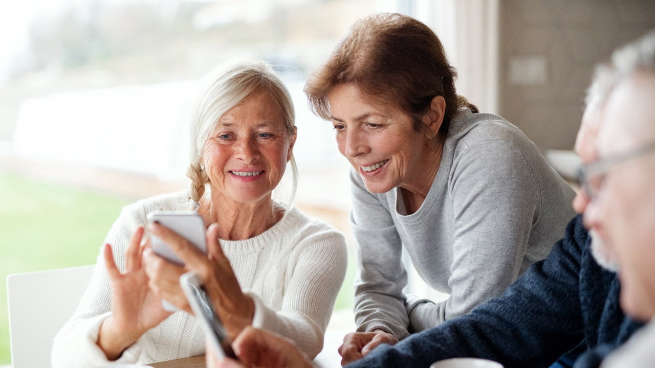two senior women looking at phone and smiling