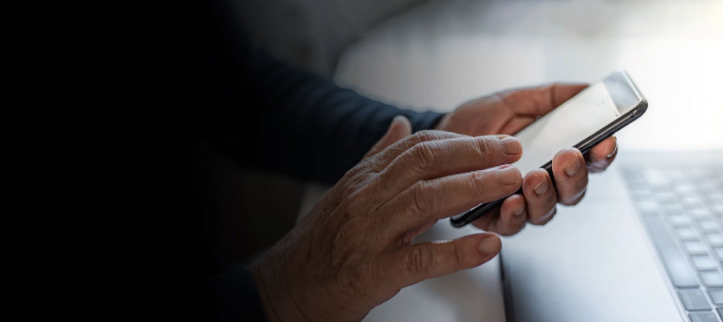 hands using smartphone near laptop