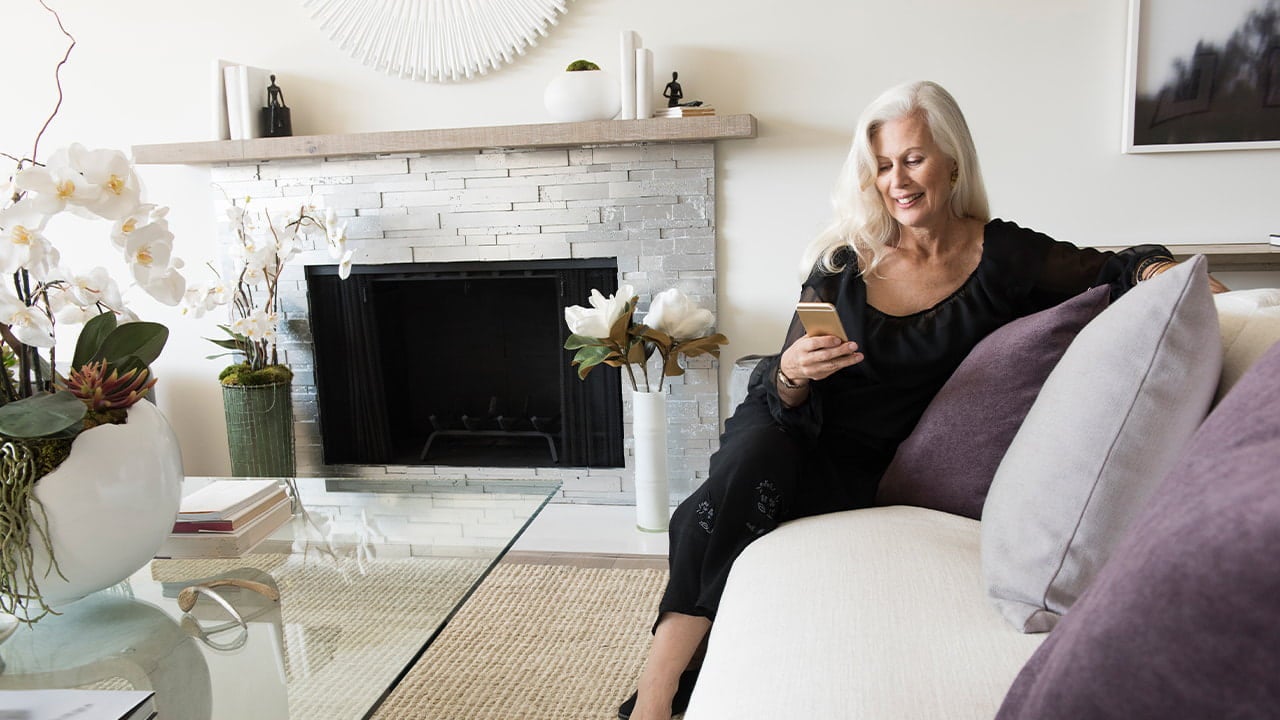 senior woman using phone on sofa