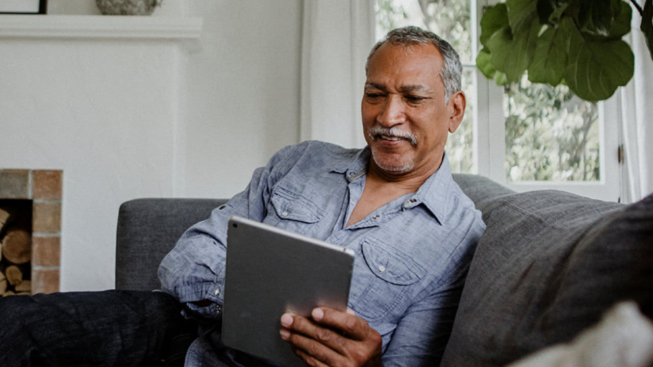 smiling man reads digital tablet