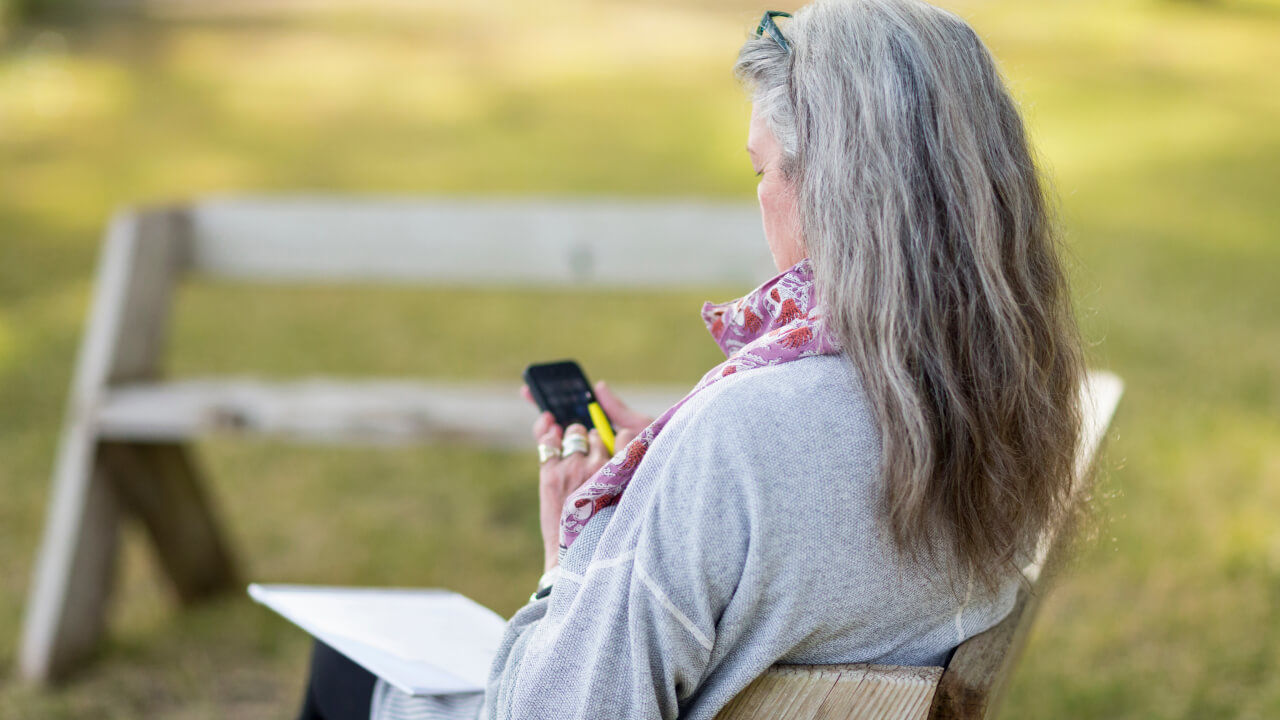 woman outdoors uses black cellphone