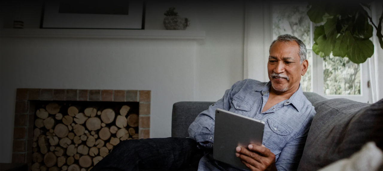 smiling man reads digital tablet