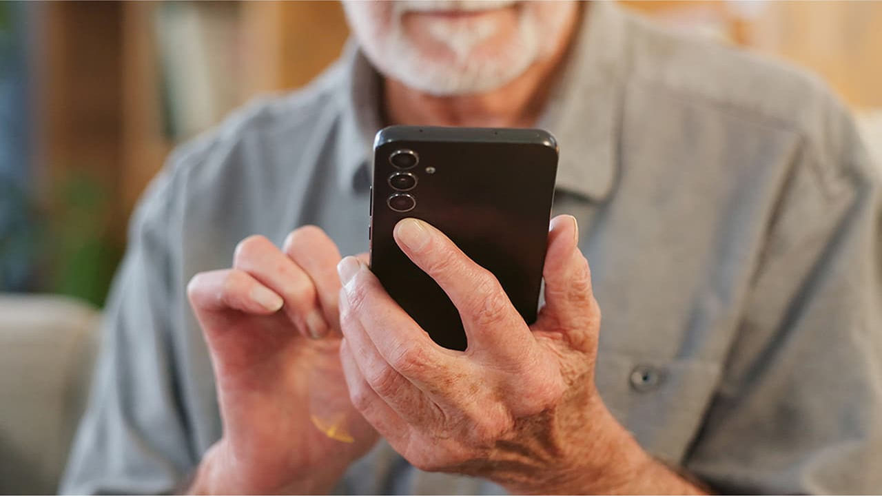 senior man with phone in hand living-room