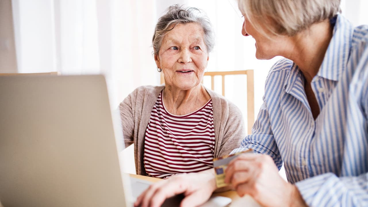 woman helps older woman on laptop