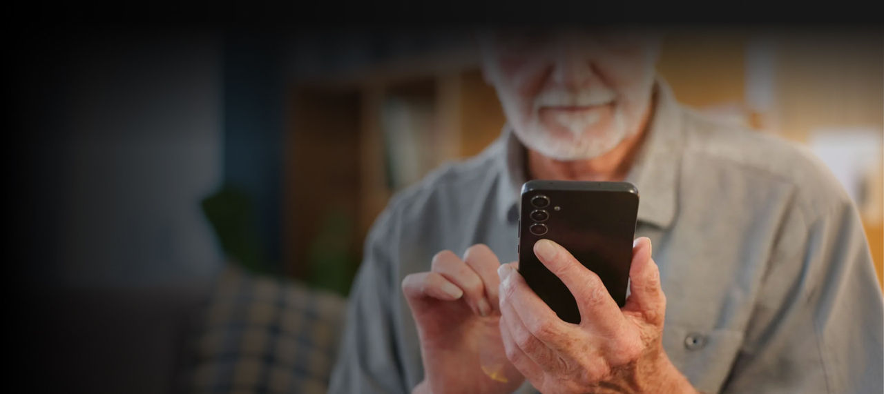 senior man using smartphone in room