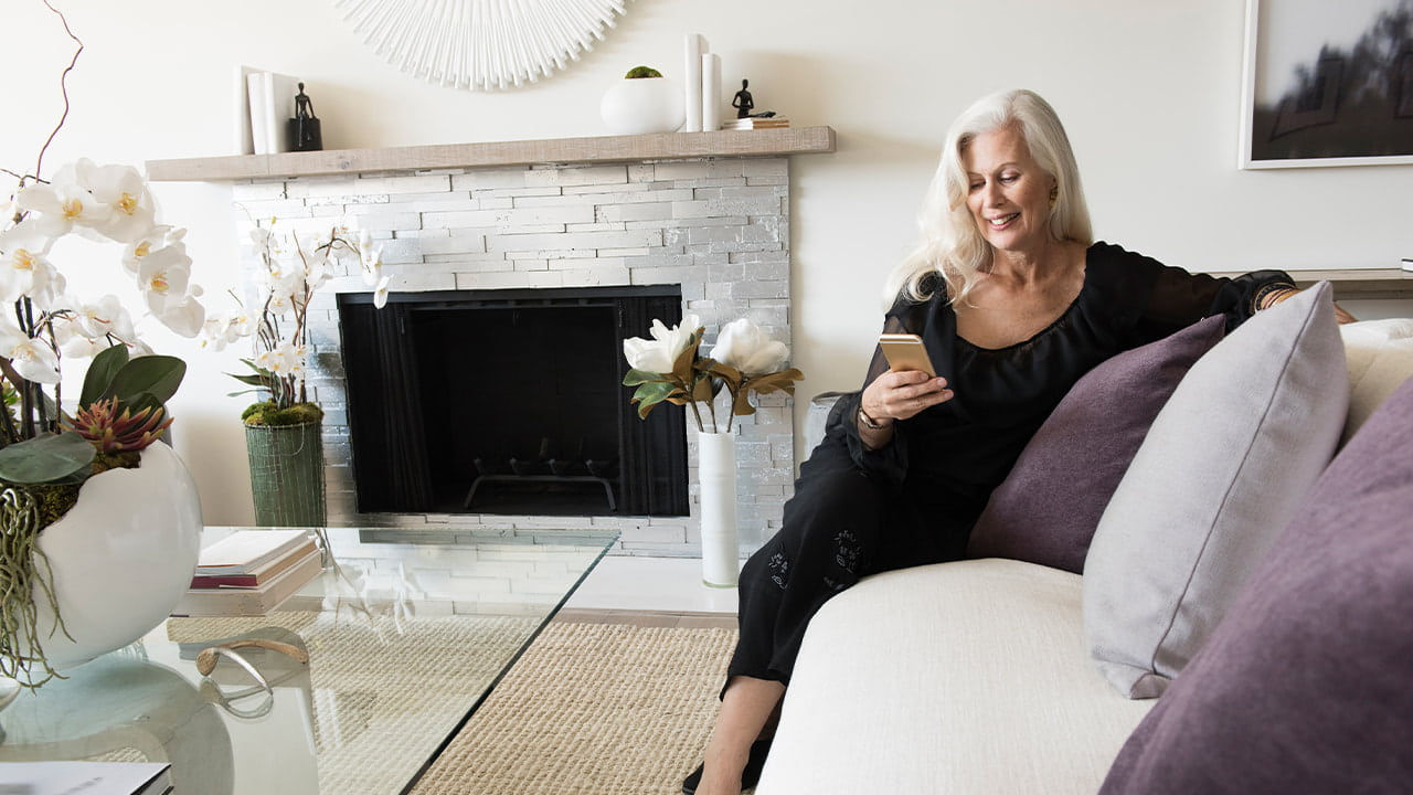 senior woman using phone on sofa