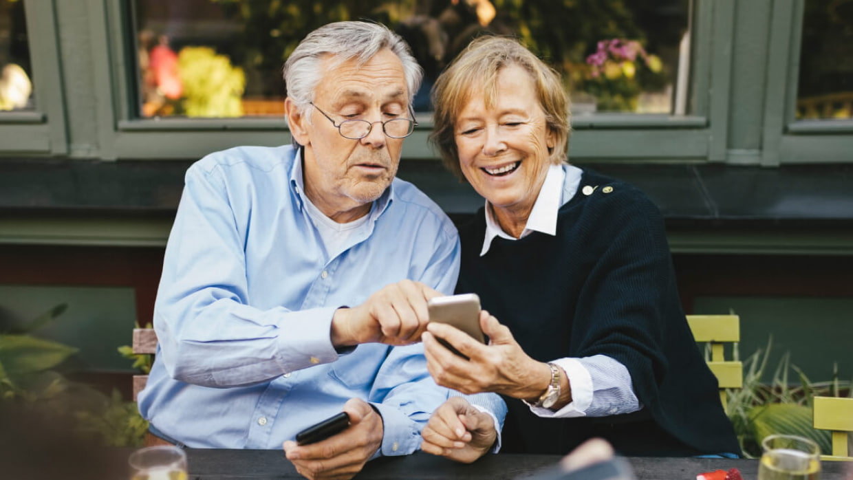 senior couple using devices at cafe