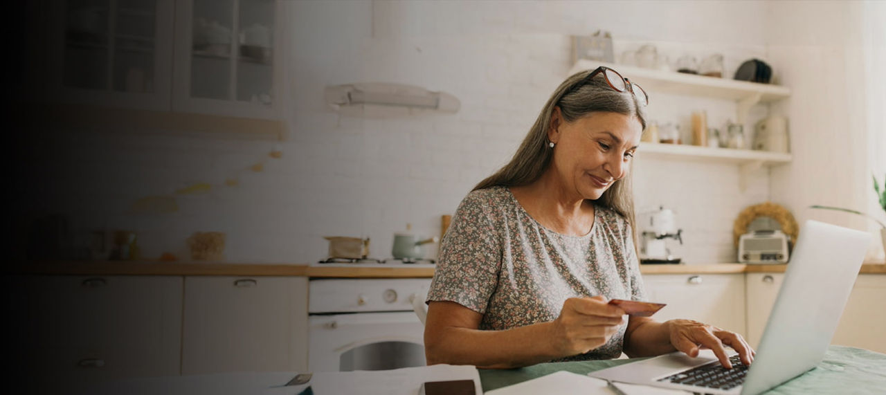 senior woman paying online with card and laptop