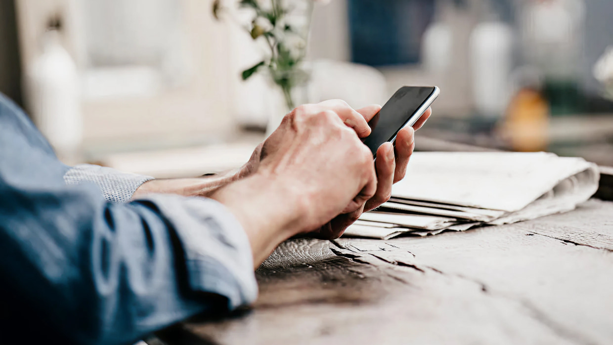 close up of hands using smartphone on wooden table