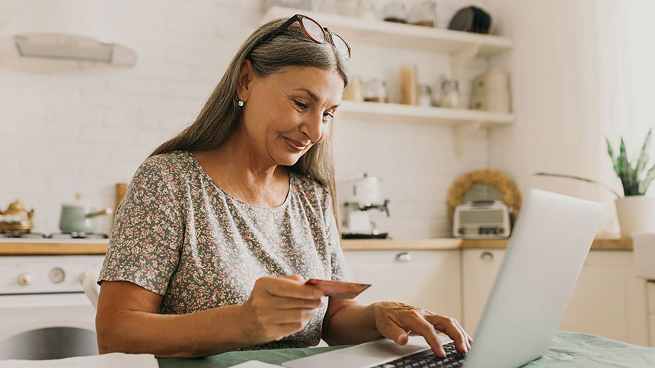 senior woman paying online with card and laptop